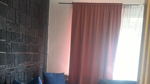 A room with a bed, a sofa, a chair, and a brick wall. - Apartment Close to Stockholm City (Hägersten)