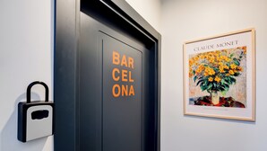 Eine Tür mit orangefarbenem Schriftzug "BARCELONA", einem Vorhängeschloss und einem gerahmten Gemälde von Claude Monet an der Wand.