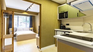 Ein kleines Hotelzimmer mit Bett, einer kleinen Küchenzeile und Blick ins Freie.