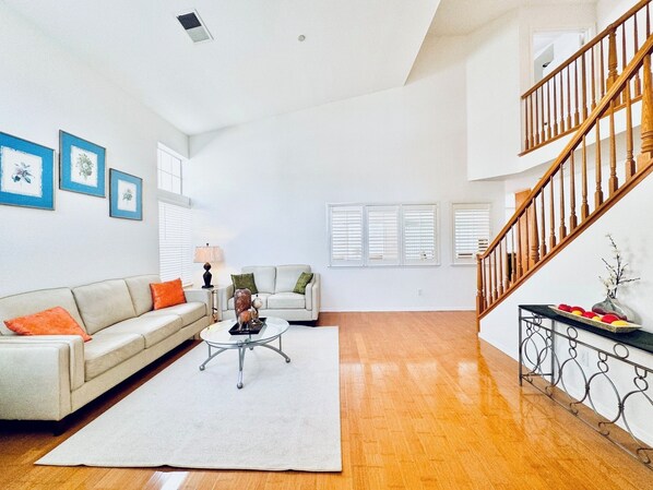 A spacious living room with a sofa, coffee table, and a staircase.