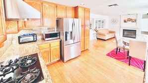 A modern kitchen with wooden cabinets, a built-in microwave, a stainless steel refrigerator, and a gas stove.