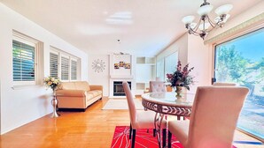A modern living room with a beige sofa, a glass coffee table, and a red patterned rug.
