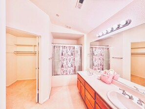 A bathroom with a shower, a vanity with a mirror, and a towel rack.