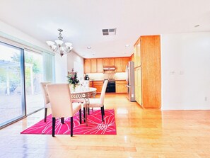 A modern kitchen with wooden cabinets, a stainless steel refrigerator, and a dining area with a round table and chairs.