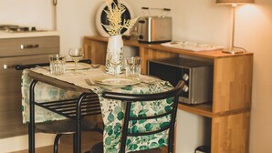 A dining area with a table set for four, a toaster, a lamp, and a shelf with decorative items. - Chic apartment between Munich and Lake Starnberg (Gauting)