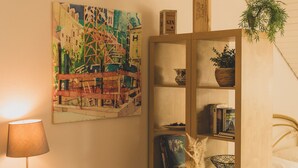 A room with a bookshelf, a lamp, a painting, and a potted plant. - Chic apartment between Munich and Lake Starnberg (Gauting)