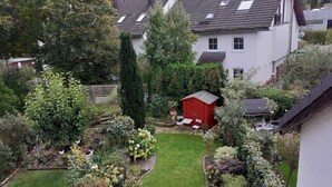 A residential garden with a red shed, a lawn, and various plants. - Chic apartment between Munich and Lake Starnberg (Gauting)