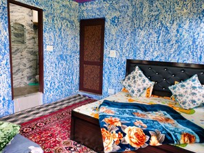 A bedroom with a bed, a wooden door, and a patterned wall. - Navmint's Nami Homes By GRB (Patna)