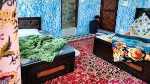 Ein Zimmer mit zwei Betten, einem gemusterten Teppich und einer blumigen, blauen Wand.