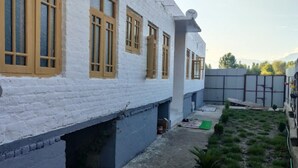 Ein weißes Gebäude mit gelb gerahmten Fenstern und einem kleinen Garten.