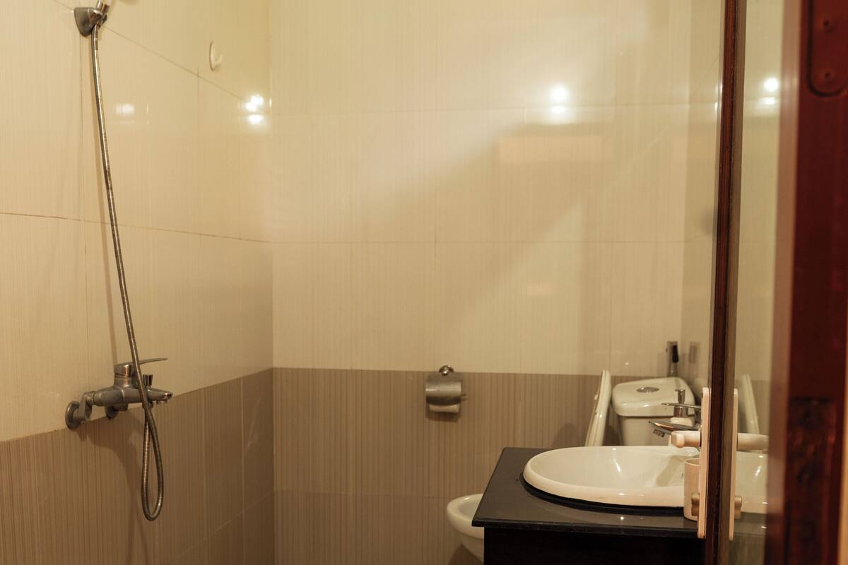 Une salle de bain équipée d’une douche, de toilettes, d’un lavabo et de carreaux de sol à motifs.