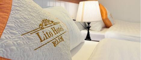 A hotel room with a bed, pillows, and a bedside lamp.