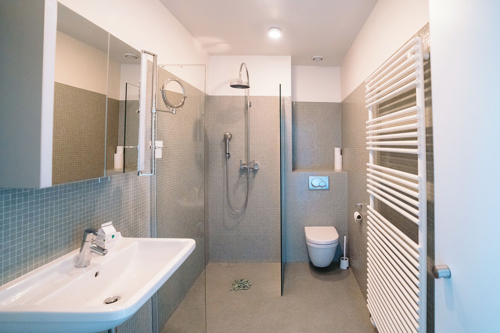 Un baño moderno con ducha de vidrio, lavamanos blanco y retrete.