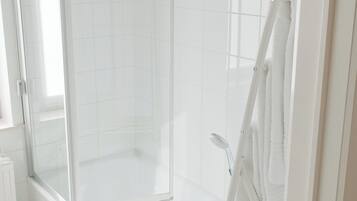 A modern bathroom with a glass-enclosed shower, a white bathtub, and a towel rack.