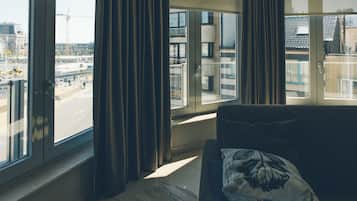 Una sala de estar moderna con un ventanal grande, un sofá y cortinas.