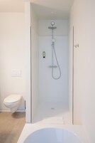 A modern bathroom with a glass-enclosed shower, a white toilet, and a bathtub.