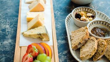 Una tabla de quesos con varios tipos de queso, uvas y pan sobre una tabla de madera.
