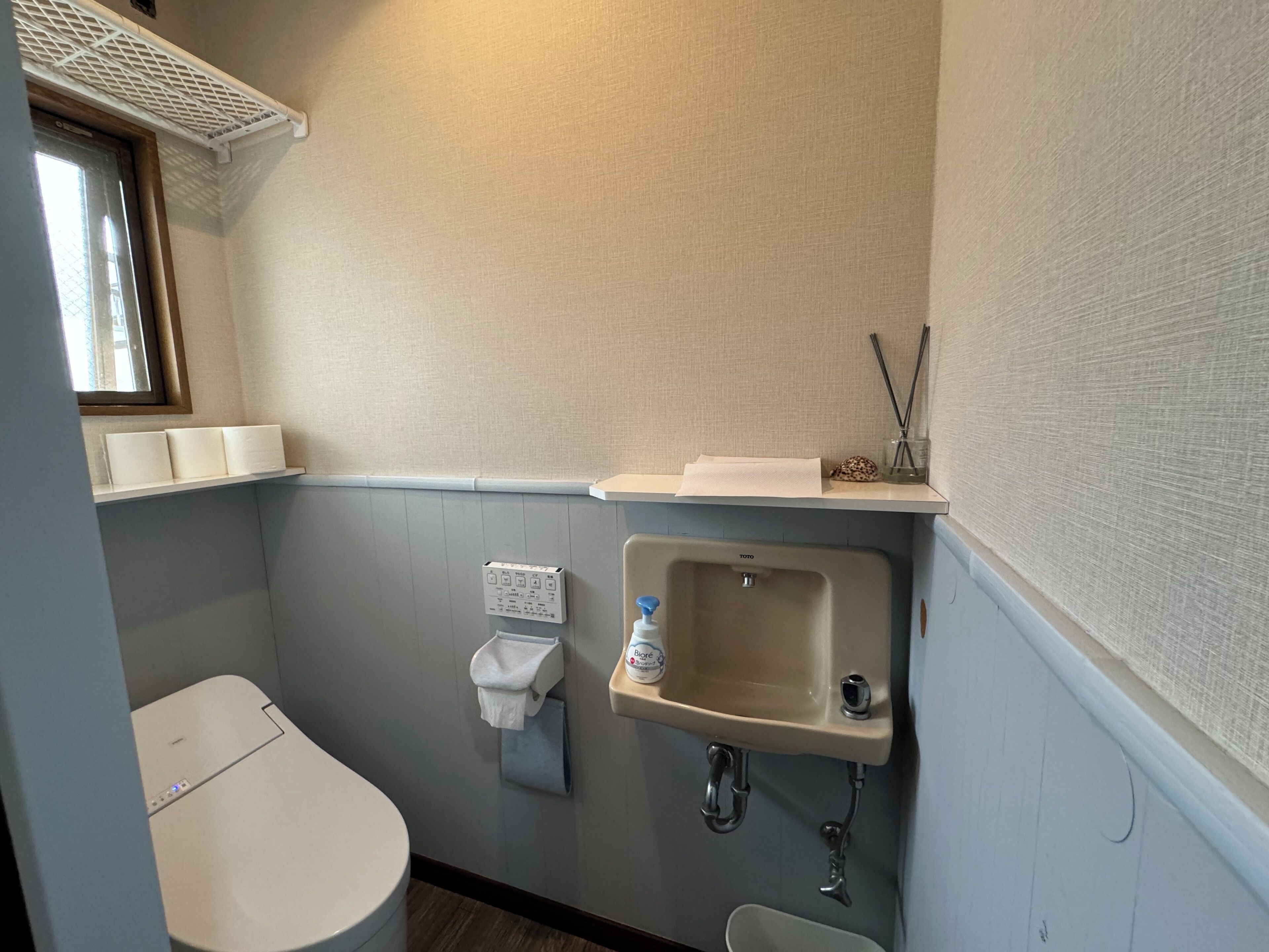 Une petite salle de bain avec des toilettes, un lavabo et une fenêtre.
