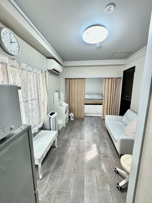 A compact hotel room with a bed, a sofa, a desk, a TV, and a bathroom. - Kobayashi Building (Tokyo)