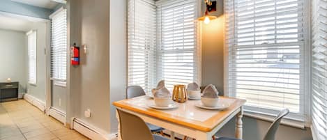 A dining area with a table set for four, two chairs, and a window with blinds.