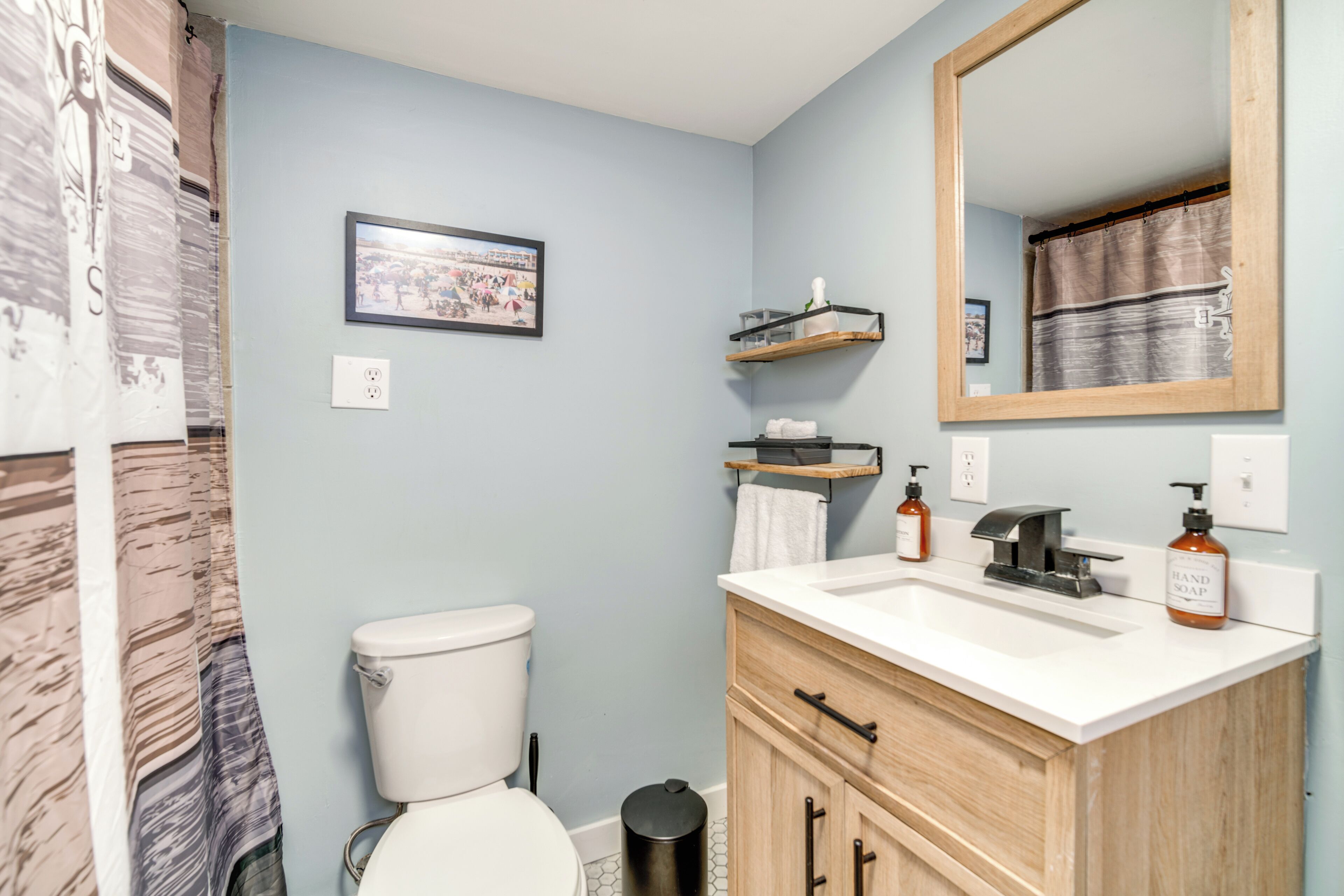 A bathroom with a toilet, sink, mirror, and towel rack.