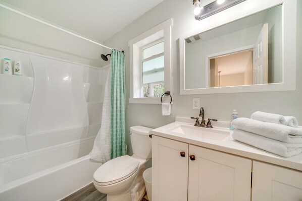 Une salle de bain équipée d’une baignoire, de toilettes, d’un lavabo et d’un miroir.