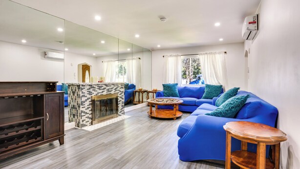 A modern living room with a blue sofa, a wooden coffee table, and a fireplace. - 4 Mi to Nyc, Shared Yard: Englewood Apartment! (Englewood)