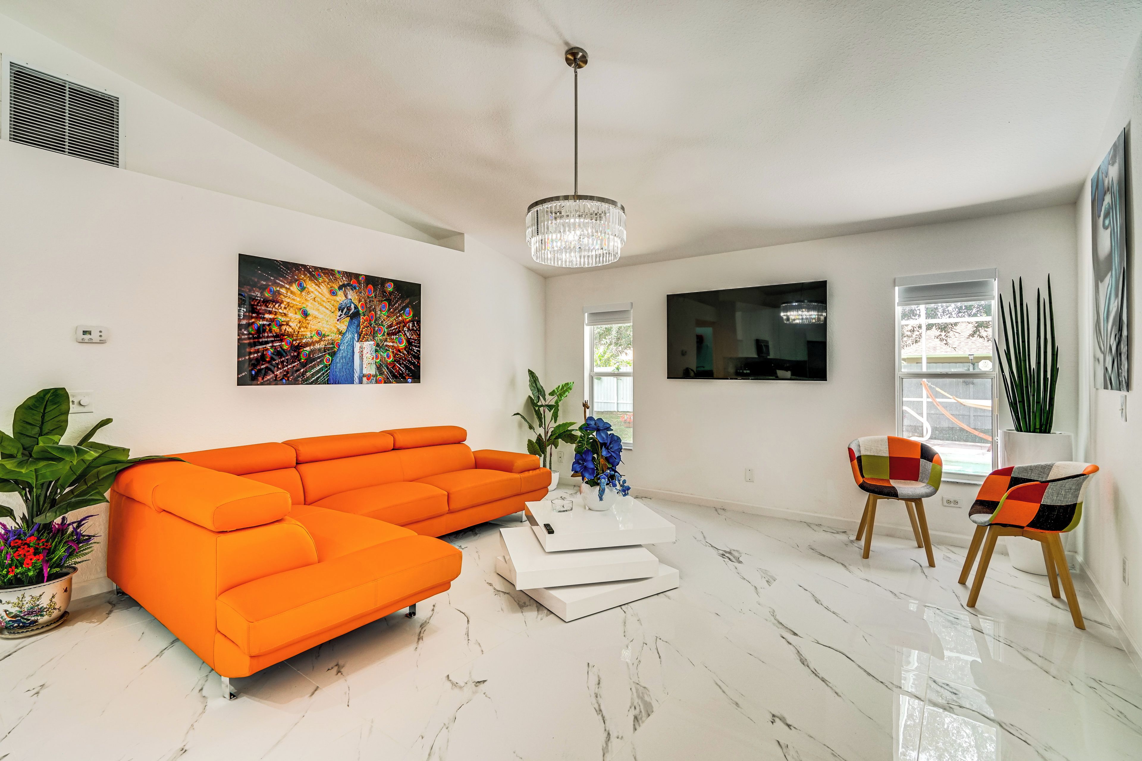 Una sala de estar moderna con un sofá modular, una mesa de centro, dos sillones, una araña y obras de arte en las paredes.