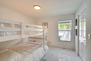 A bedroom with bunk beds, a window with a view, and a door with a light switch. - Cape Coral Pool Home w/ Outdoor Kitchen & Games (Cape Coral)
