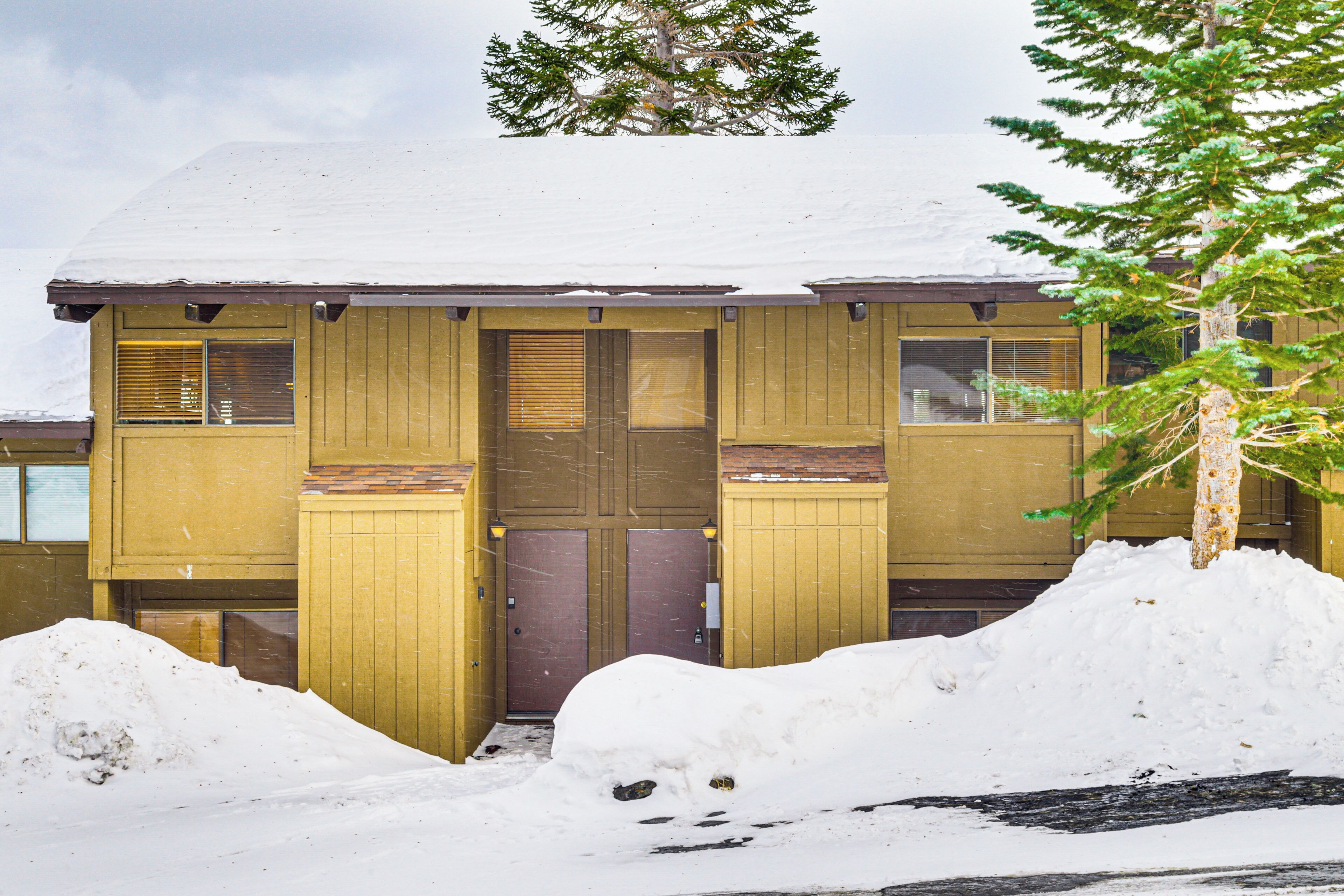 A two-story wooden building with a snow-covered roof and a front door.