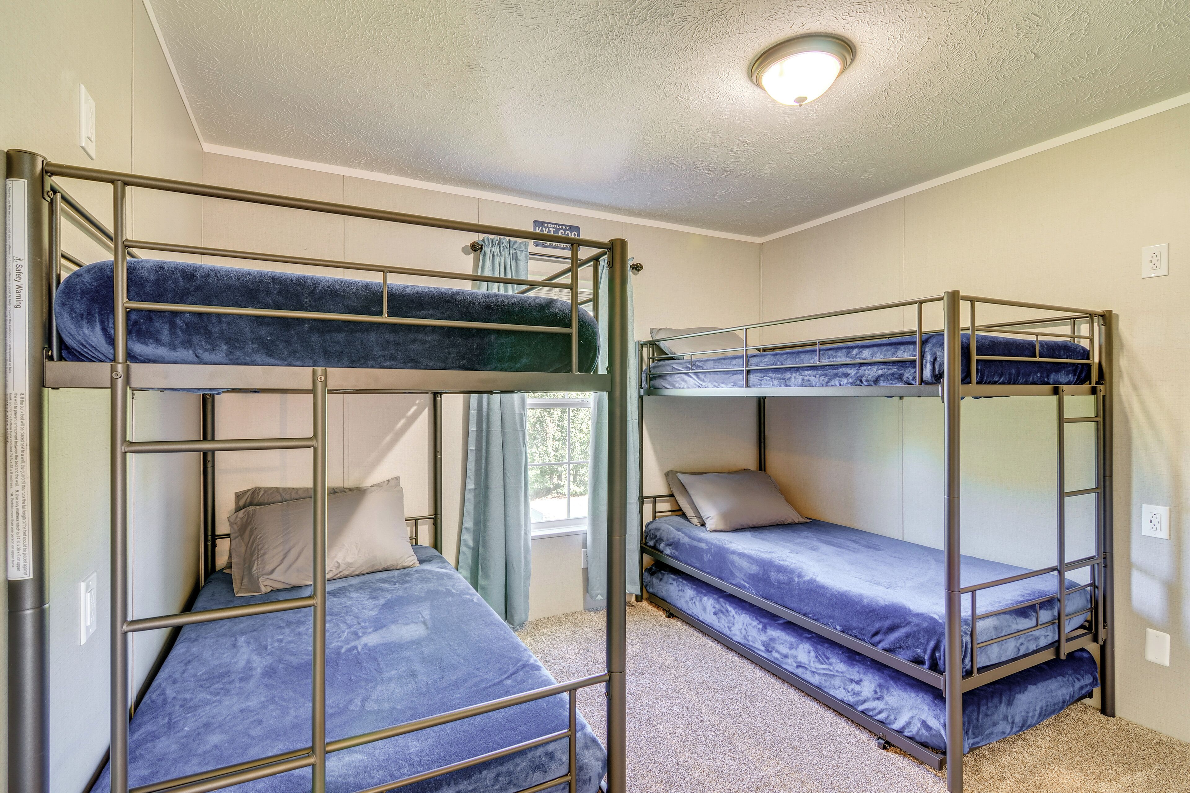 Un dormitorio con literas, una ventana con cortinas y una lámpara en el techo.