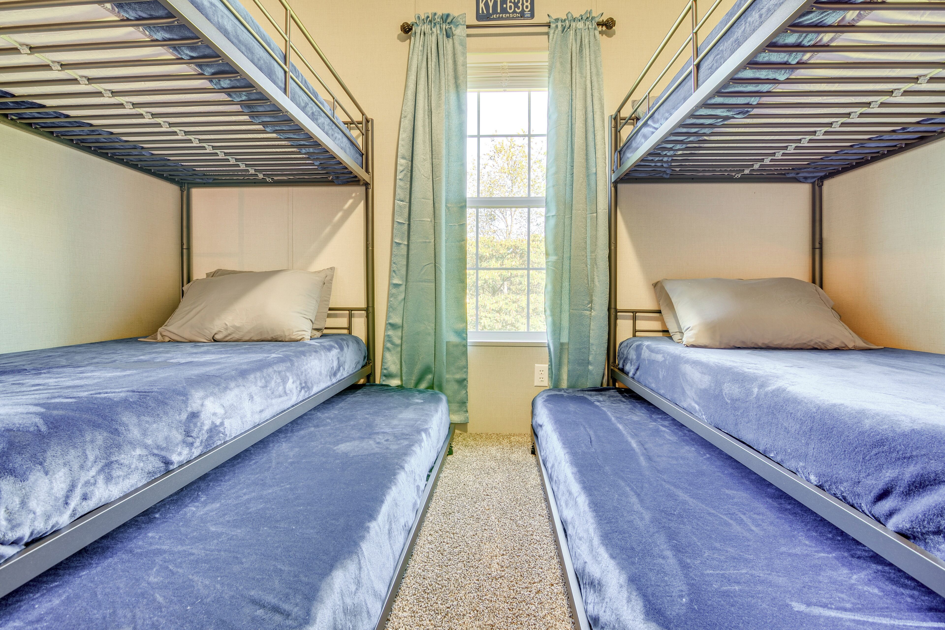 Une chambre de dortoir avec des lits superposés, une fenêtre avec des rideaux et un petit cadre photo accroché au mur.
