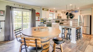 Une cuisine dotée d’un îlot central, de tabourets de bar et d’un tonneau en bois servant de base à la table.