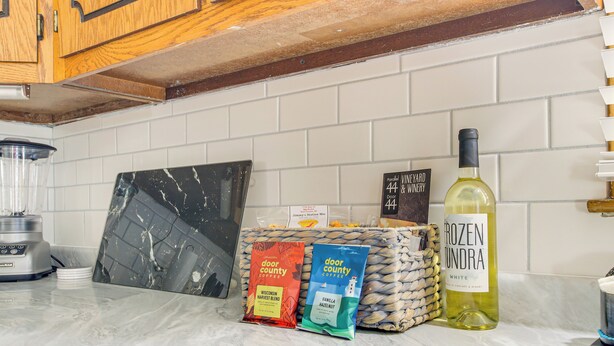 A kitchen counter with a coffee maker, a bottle of wine, and two coffee packets. - < 1 Mi to Lambeau Field: Green Bay Home w/ Grill! (Green Bay)