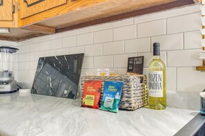 A kitchen counter with a coffee maker, a bottle of wine, and two coffee packets. - < 1 Mi to Lambeau Field: Green Bay Home w/ Grill! (Green Bay)