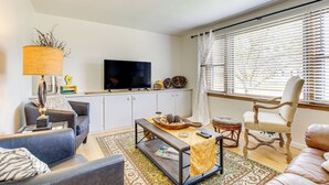 A living room with a sofa, a coffee table, a TV, and a window with blinds. - < 1 Mi to Lambeau Field: Green Bay Home w/ Grill! (Green Bay)