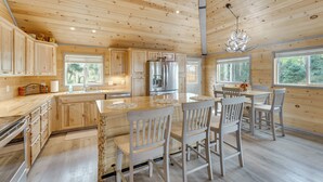 A spacious wooden cabin with a large kitchen, dining area, and multiple windows offering views of the forest. - Mountain Views: Cabin in Fort Garland Near Hiking (Fort Garland)