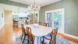 A dining area with a chandelier, wooden chairs, a table, and a patterned rug. - Spacious Home w/ Hiking Trail Access in Bristol! (Bristol)