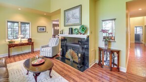 A spacious living room with hardwood floors, a fireplace, a striped armchair, and a coffee table. - Spacious Home w/ Hiking Trail Access in Bristol! (Bristol)