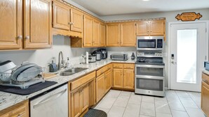 Una cucina con mobili in legno, elettrodomestici in acciaio inossidabile e scolapiatti.