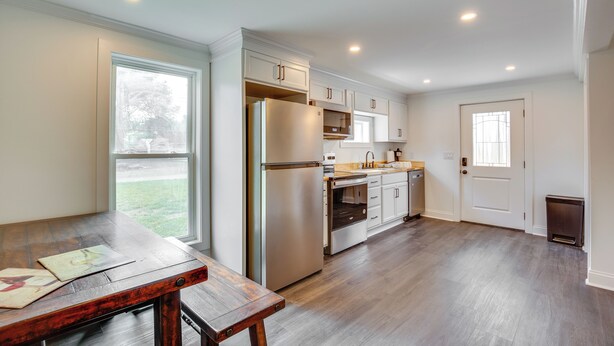 A modern kitchen with white cabinets, stainless steel appliances, and a wooden dining table. - Walk to Winery: Holt Home 8 Mi to State Park! (Holt)