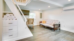 A spacious living room with a wooden floor, a sofa, a chair, and a staircase with a built-in storage unit. - Walk to Winery: Holt Home 8 Mi to State Park! (Holt)