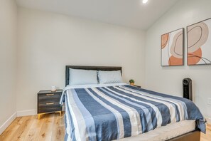 Un dormitorio con cama, mesita de noche, calentador de pared y arte abstracto en la pared.