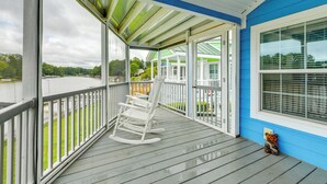 A covered porch with a rocking chair and a small bear decoration.