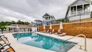 A swimming pool with lounge chairs, a covered seating area, and a brick wall.