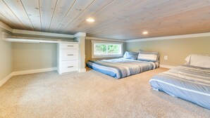A bedroom with a sloped ceiling, a window, a bed, and a built-in storage unit. - Lake Norman Getaway w/ Pool Access + Kayaking! (Sherrills Ford)