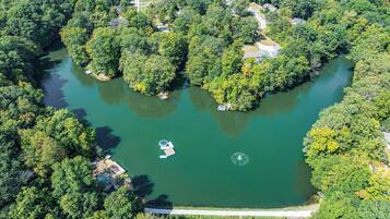 Une vue aérienne d’un lac entouré d’une forêt dense, avec un petit quai et un bateau.