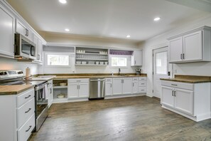 A modern kitchen with white cabinetry, a stainless steel dishwasher, and a wooden countertop. - Walk to Winery: Family-friendly Holt Getaway (Holt)
