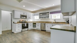 A modern kitchen with white cabinetry, a wooden countertop, and built-in appliances. - Walk to Winery: Family-friendly Holt Getaway (Holt)