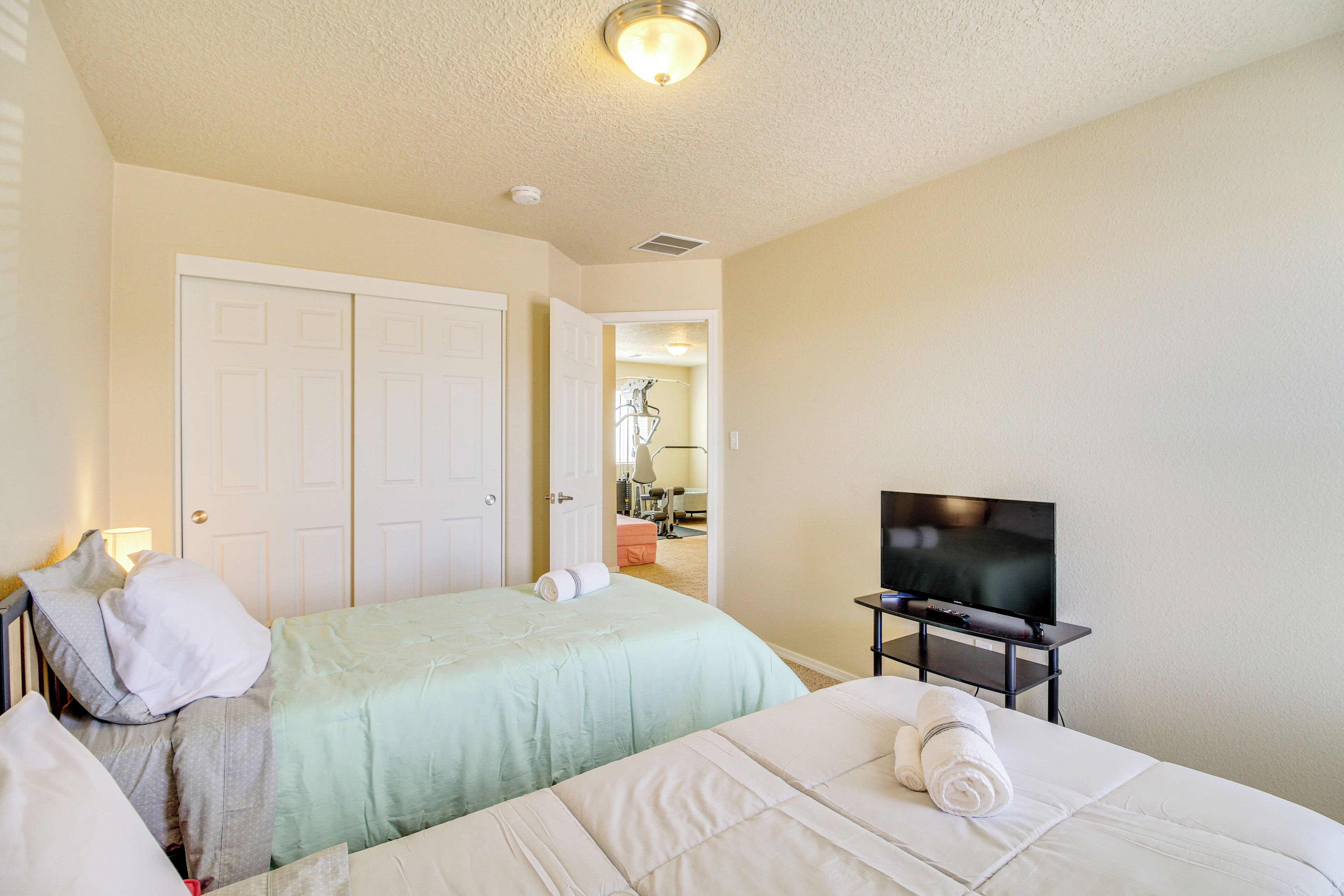 Habitación de hotel con dos camas, televisión y puerta que da a un baño.